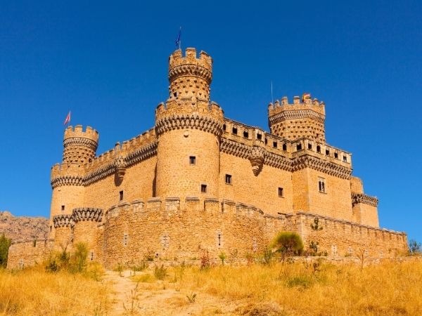 Castle Manzanares el Real, impressive 15th-century Gothic fortress near Madrid, Spain, with robust towers and stone walls under bright blue sky