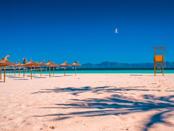 Beautiful Playa de Muro beach with turquoise water, sandy shore, and mountain views in Mallorca, Spain