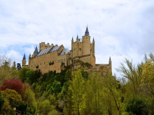 Alcazar Segovia fairy-tale castle on the hilltop in Segovia Spain, iconic medieval fortress with spires and turrets overlooking the valley