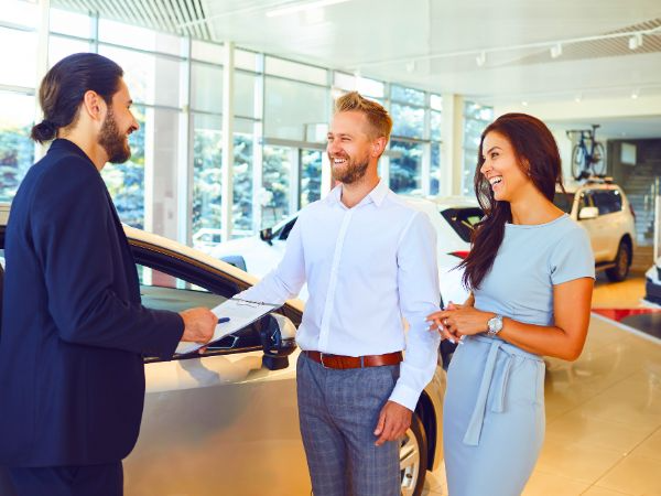 Happy couple renting a car at Final Rentals in Playa de Muro with friendly service representative