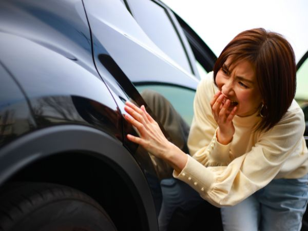 Tourist inspecting rental car for damage before pickup to avoid charges in Playa de Muro Mallorca