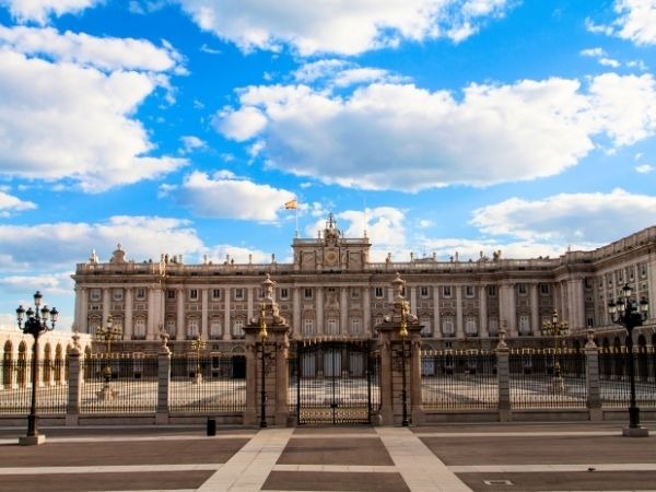 Royal Palace Madrid Spain exterior view on a clear blue sky day, majestic Baroque facade of the Palacio Real de Madrid with ornate gates and statues